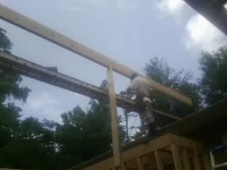 Carpenter setting a ridge beam over a new addition frame — Ice Dam Removal by Roofing Brothers in Archer