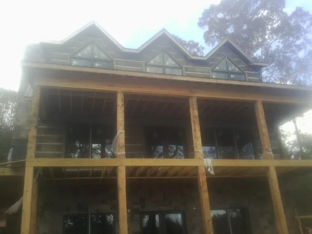 Dormers and porch framing on a large log home under construction — Roof Coating work by our crew in Archer