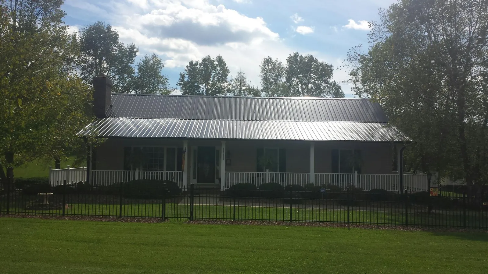 Gray metal roof on a brick ranch with a full width front porch — Gutter Guard Installation work by our crew in Archer